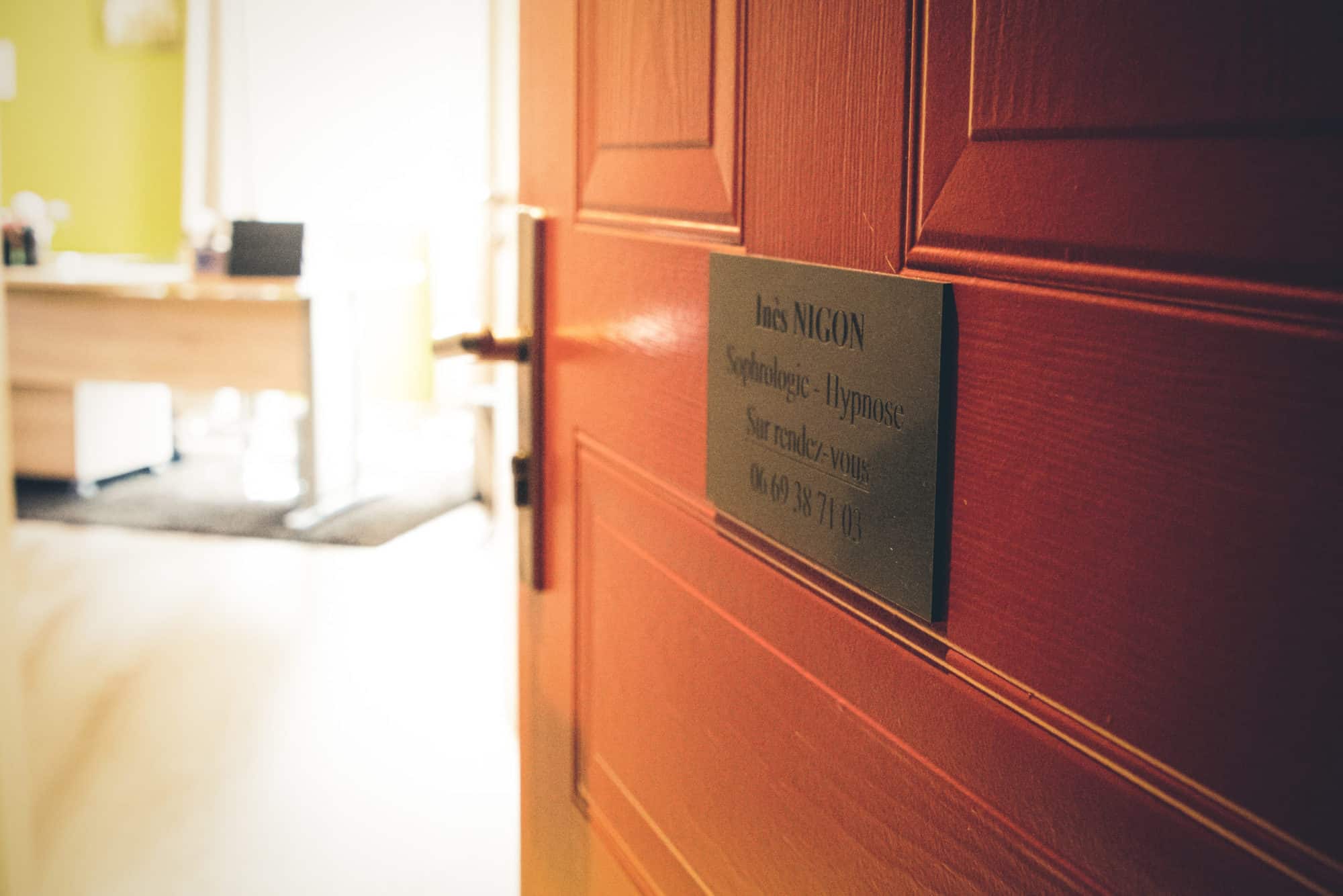 Porte d'entrée du cabinet d'Inès Nigon, plaque « Inès Nigon — Sophrologie - Hypnose — Sur rendez-vous »